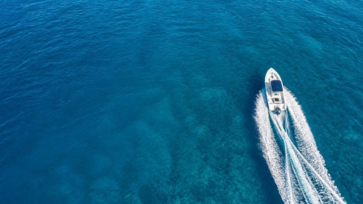 Aerial view of a white center-console fishing boat and its wake on open blue water